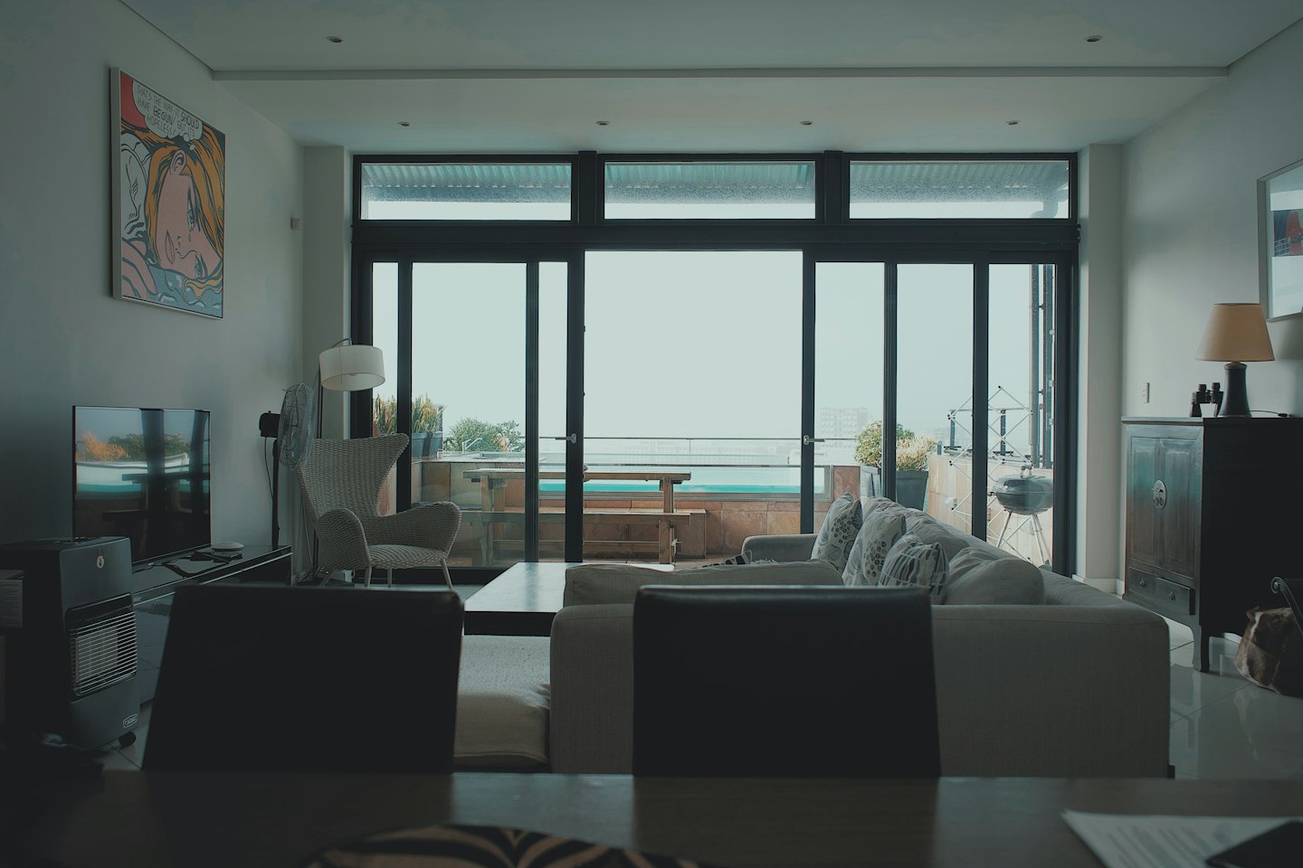 Salon moderne avec vue sur la piscine et la ville au loin.