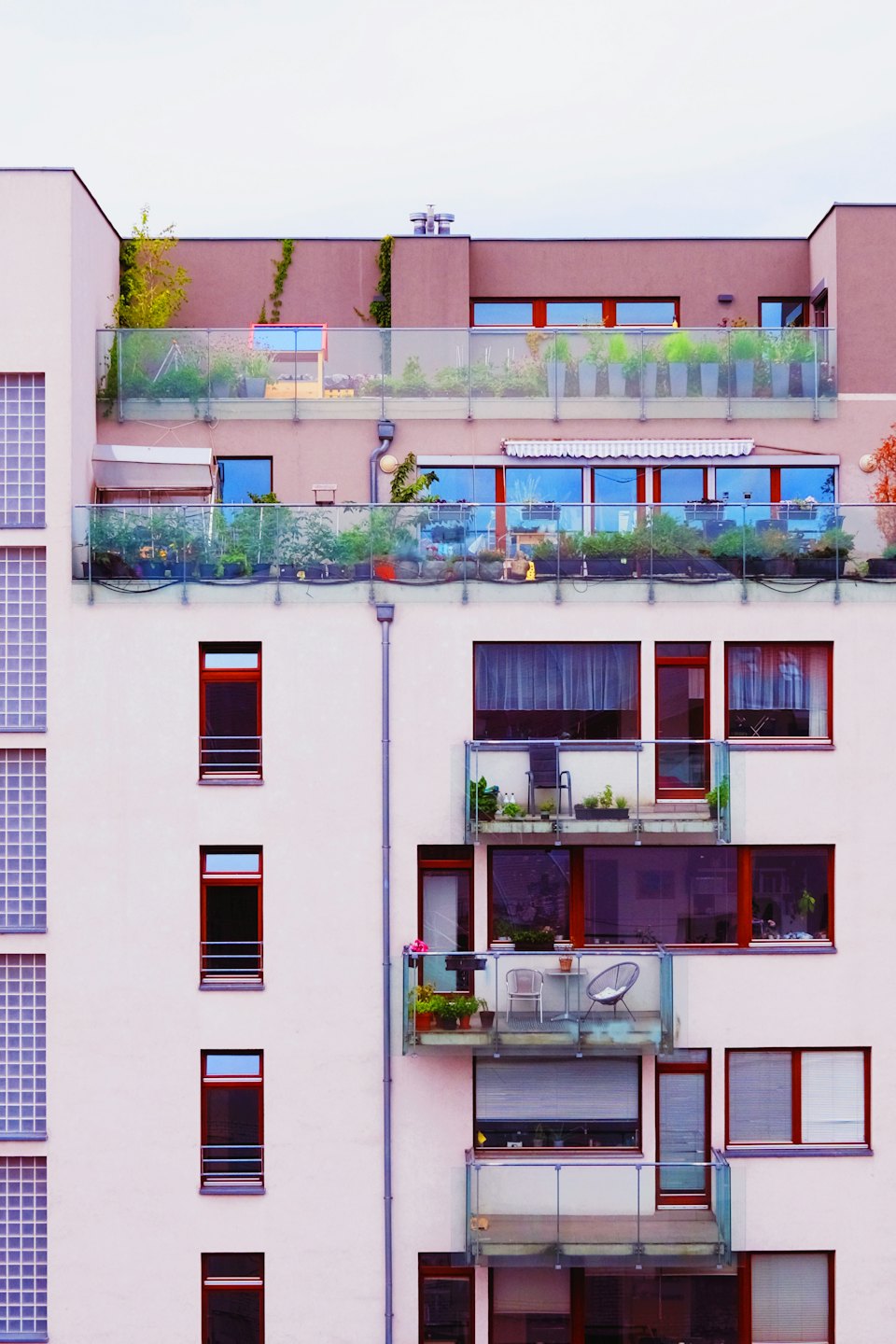 Immeuble d'appartements moderne avec balcons et jardin sur le toit.