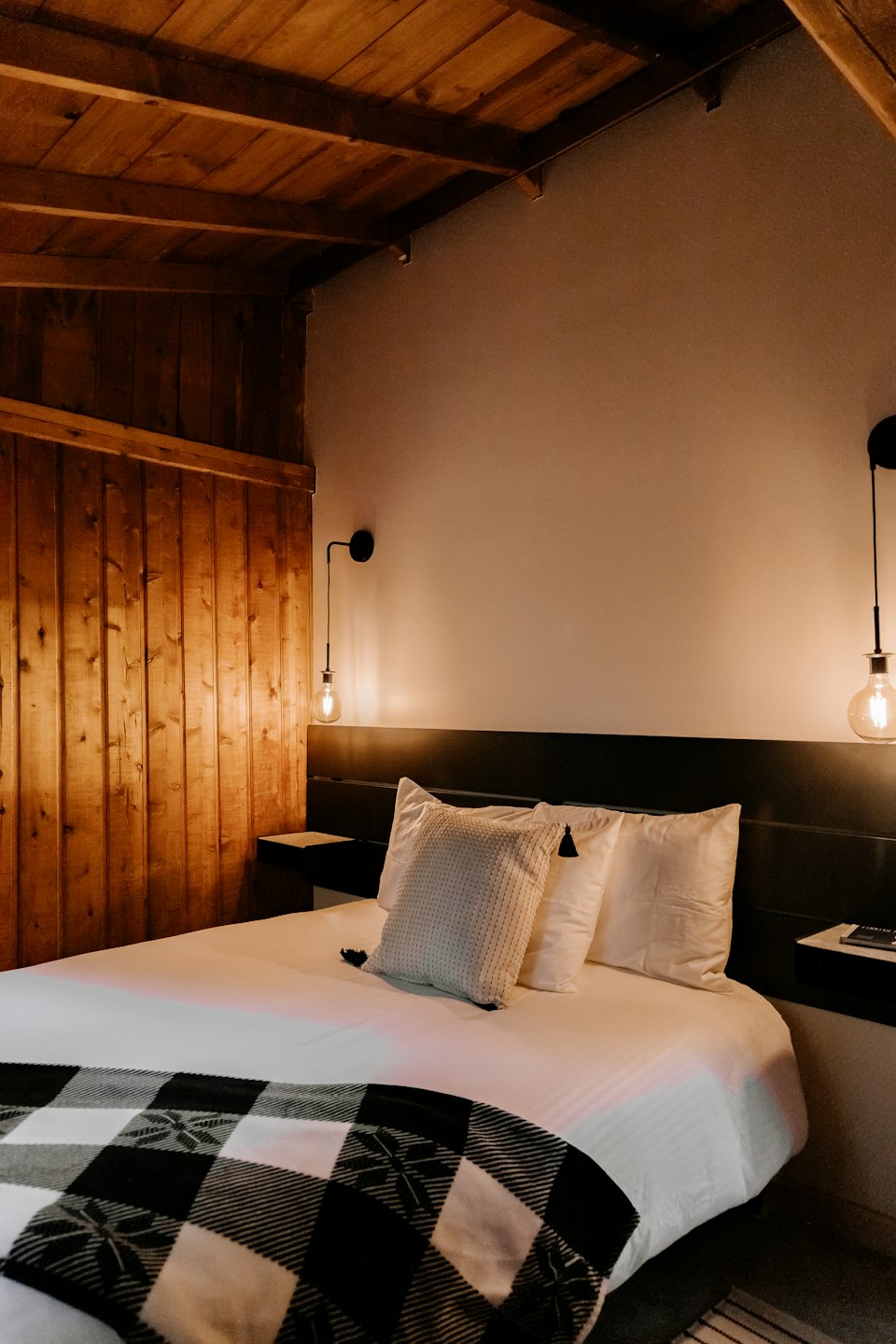 Chambre confortable avec mur en planches de bois et lit bien fait.