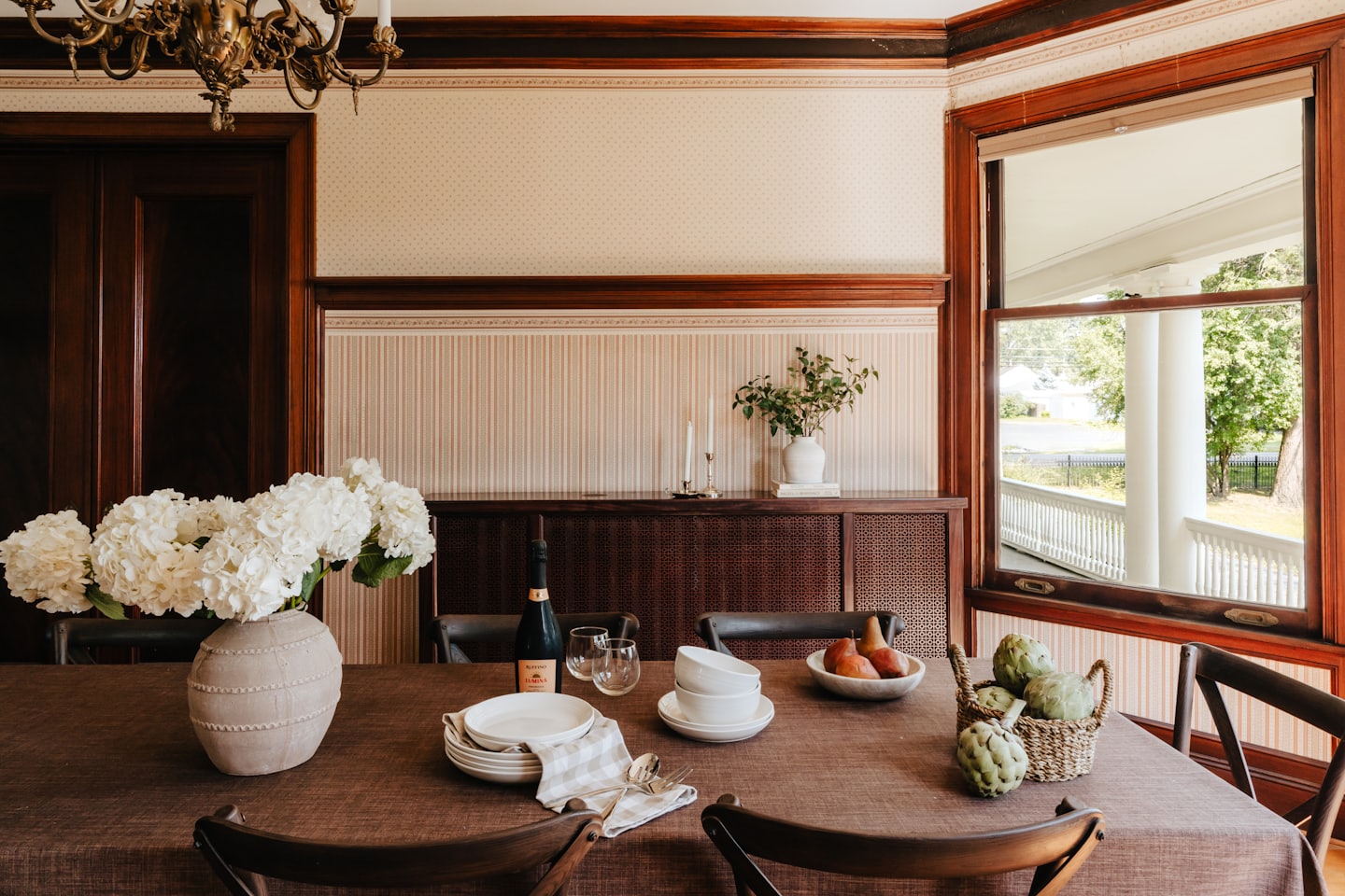 Table de salle à manger dressée avec des assiettes blanches et une bouteille de vin.